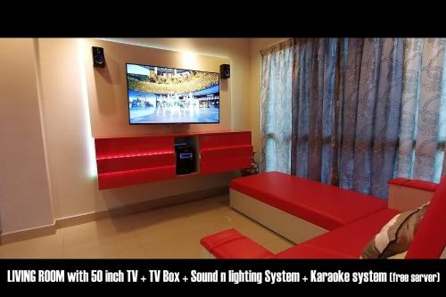 峇六拜Penang karaoke Ruby Townhouse 1st floor的一间带电视和红色沙发的客厅