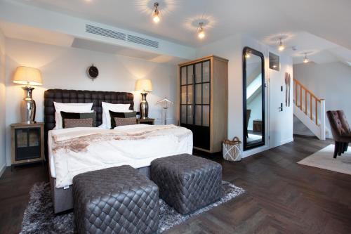 特希尔Hotel Achterum Greetsiel的一间卧室配有一张大床和两张搁脚凳