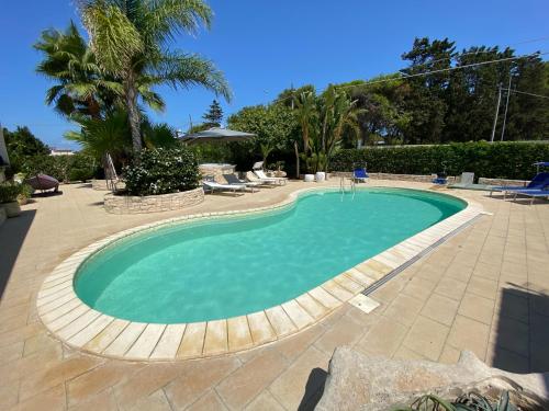 托雷奇安卡Buen Retiro - Villa con piscina vicino Lecce a 450m dal mare的庭院里的大型游泳池,设有椅子和树木