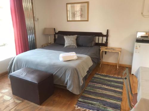 克莱克斯多普Serenity Guesthouse的一间卧室配有一张大床、一张搁脚凳和一张桌子