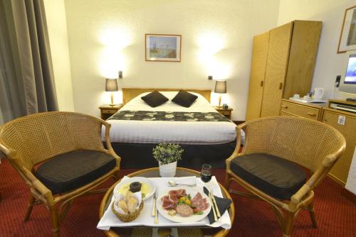格勒诺布尔安格勒特里格勒诺布尔中心酒店的酒店客房,配有一张床和两把椅子,并提供一个食品托盘