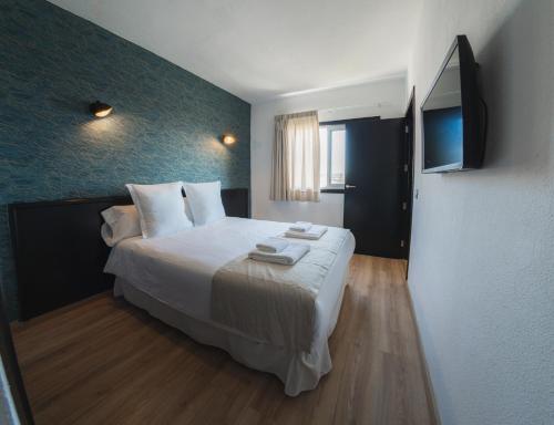 厄尔梅达诺Hotel Ventus的一间卧室配有一张带白色床单的大床和电视。