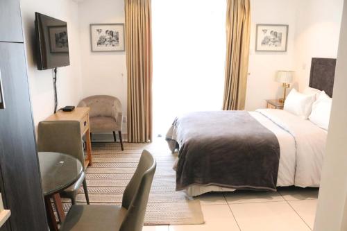 阿克拉APARTMENTS GH - Accra - Cantonments - Embassy Gardens的酒店客房,配有床、桌子和椅子