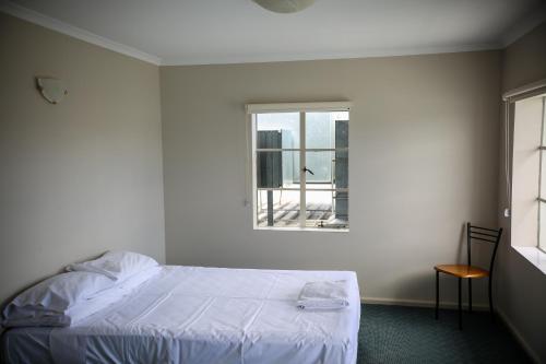 LindisfarneBeltana Hotel的白色的卧室设有床和窗户