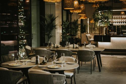 利马索尔The Icon Limassol的餐厅设有桌椅和吊灯。