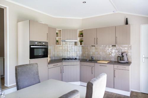 克诺克－海斯特luxe cottage knokke heist的厨房配有白色橱柜和桌椅