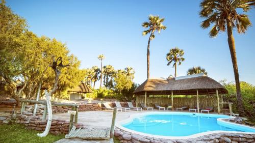 PalmPalmwag Lodge的一个带凉亭和棕榈树的游泳池