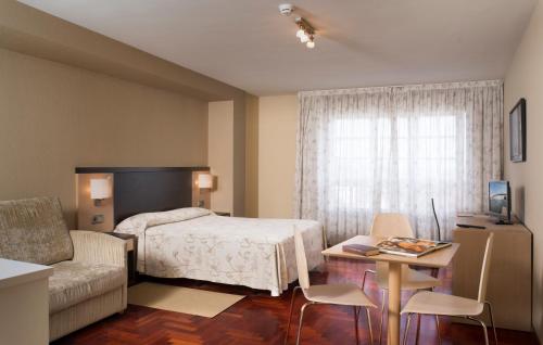 拉科鲁尼亚Apartamentos Portazgo的一间卧室配有一张床、一张桌子和一张沙发