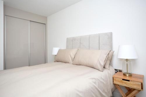赫尔Luxury Duplex 2-Bed Apartment Fruit Market Marina的白色卧室配有床和带灯的床头柜