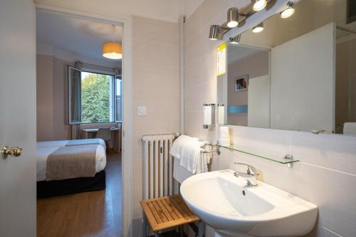 佩皮尼昂蒙蒂阿尔酒店的一间带水槽和镜子的浴室以及一张床