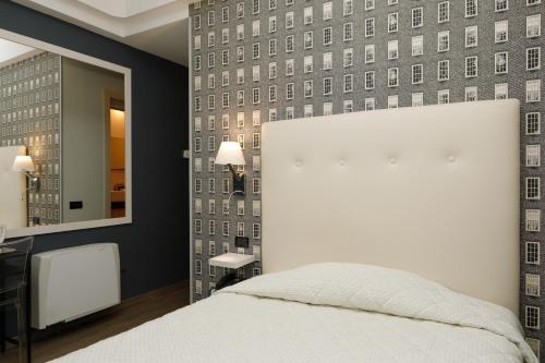 都灵兰卡斯特酒店的卧室配有白色的床和镜子
