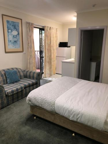 墨尔本Evancourt Motel Malvern East的一间卧室配有一张床和一张沙发,还设有一间厨房
