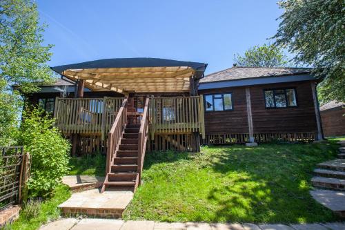 HardhamTree Tops Holiday Let & Sauna South Downs West Sussex Sleeps 10的一座带木甲板和凉亭的房子