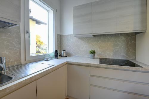 托斯科拉诺-马德尔诺Maison Bellini 4的厨房配有白色橱柜和窗户。