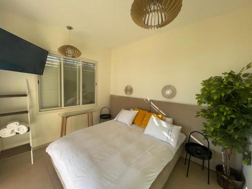 Poriyyaנוף המצוק的卧室配有白色的床和盆栽植物