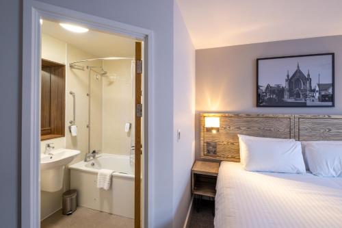 切普斯托两江马斯顿旅馆的卧室配有1张床、浴缸和水槽。