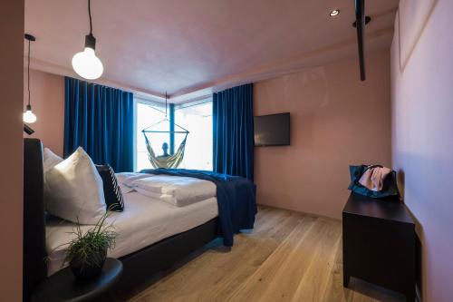 维哥迪法萨Sport Hotel Passo Carezza的一间卧室配有一张带蓝色窗帘的床和一扇窗户