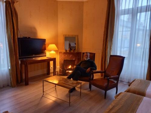 朗格勒贝勒弗德尔德郎巴特酒店的坐在带壁炉的客厅椅子上的人