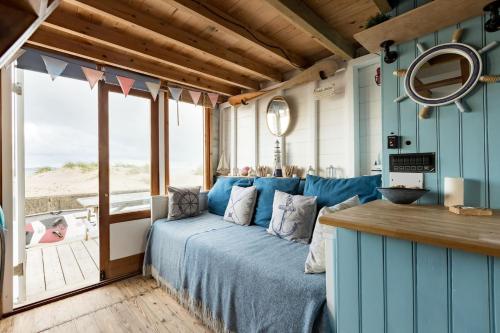 基督城Stargazing Beach Hut on Mudeford Sandbank with wake up sea views的一间卧室配有一张蓝色的床,享有海滩美景