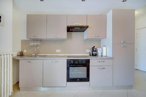 戛纳IMMOGROOM - Terrace - 2 bedrooms - Downtown - Air conditioning - Wifi的厨房配有白色橱柜和黑烤箱。
