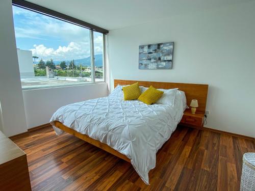 基多HERMOSO DEPARTAMENTO CON INCREIBLES VISTAS CUMBAYA的一间卧室设有一张床和一个大窗户