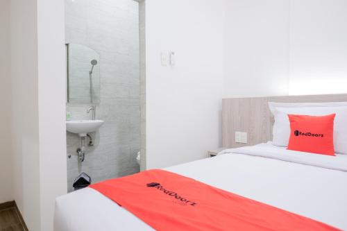棉兰RedDoorz Plus @ Jalan Juanda Medan的一间卧室配有一张带红色枕头和水槽的床