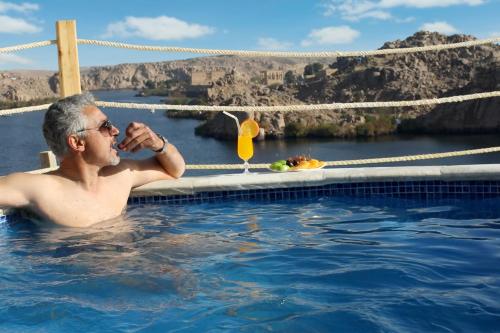 阿斯旺Benben by Dhara Hotels - Adults Only的游泳池里的男人喝一杯