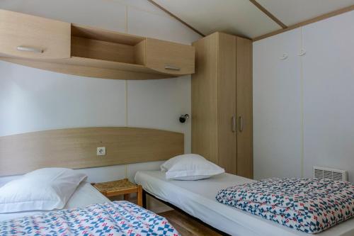 锡耶纳锡耶纳科勒维德露营酒店的小客房内的两张床,配有两张sidx sidx单人床