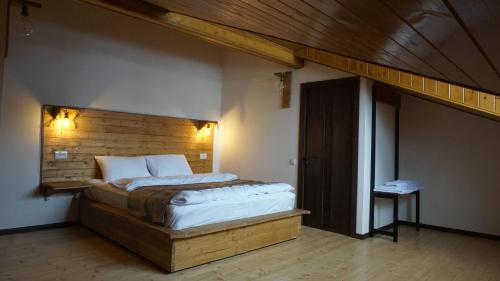 卡兹贝吉Mansarda Kazbegi的一间卧室配有一张大床和木制床头板