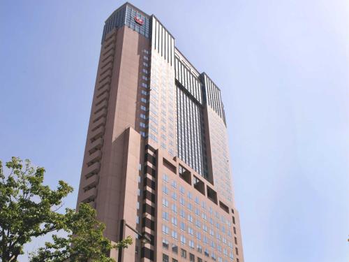 金泽金泽日航酒店的一座高大的建筑,背后是蓝天