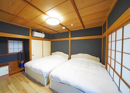 箱根Villa Liberte Hakone Gora的配有蓝色墙壁和木制天花板的2张床