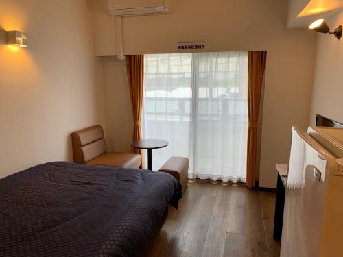 那霸Clean Hotels in Higashimachi的卧室配有床、椅子和窗户。