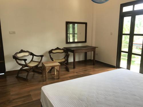 贝鲁沃勒Villa Sea Side Beruwala的一间卧室配有一张床、一张桌子和两把椅子