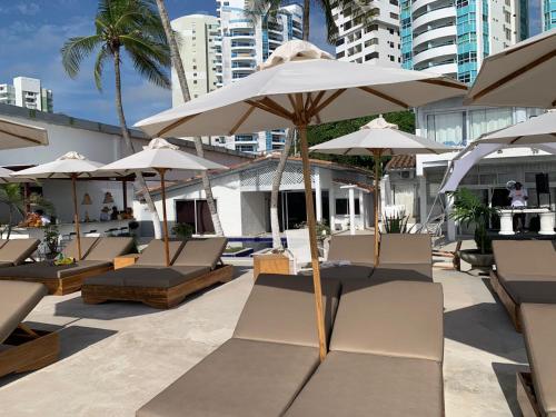 卡塔赫纳Wala beach club的庭院里摆放着一组椅子和遮阳伞