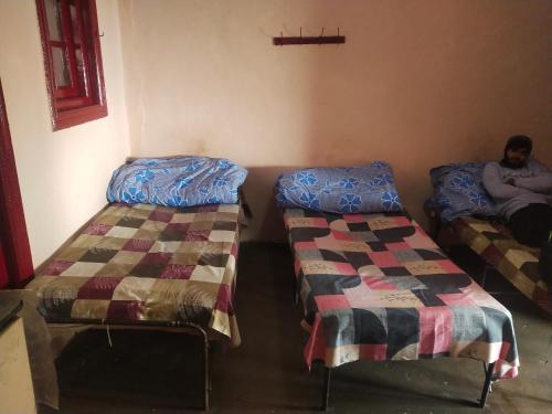 西姆拉Kumar Guest House的房间里有两张床,有男人坐在上面
