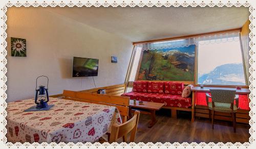 圣莫里斯堡les 3 marmottes - Les Arolles的客房设有桌子、沙发和窗户。