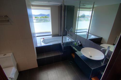 哥打京那巴鲁查亚旅馆的带浴缸、水槽和镜子的浴室