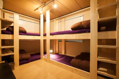 东京品川宿背包旅舍的一间客房配有两张双层床和紫色毯子