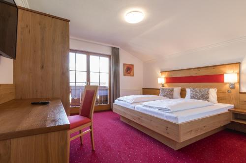 斯拉德明Landhaus Rosengartl的酒店客房设有一张大床和一张书桌。