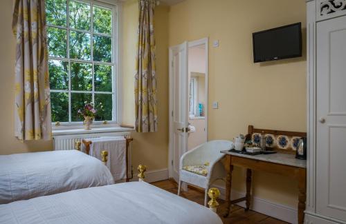 Kenton老牧师住宿加早餐旅馆的一间卧室配有一张床、一张书桌和一个窗户。