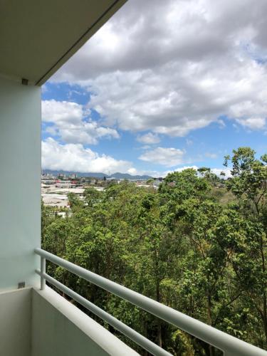 埃雷迪亚Lovely Apartment near Costa Rica airport的客房设有一个享有树木景致的阳台。