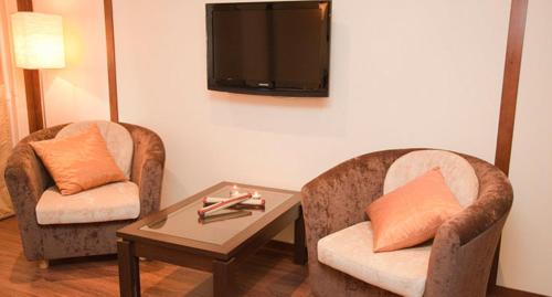 克麦罗沃Hotel Evraziya的客厅配有两把椅子、一张桌子和一台电视