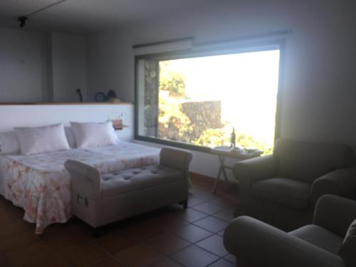 丰卡连特德拉帕尔马CASA LAS VISTAS的卧室配有床、椅子和窗户。