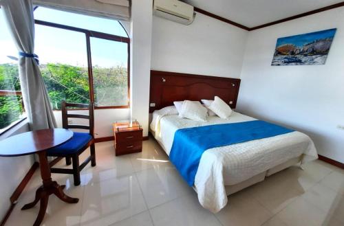 巴克里索莫雷诺港Galápagos Casa Playa Mann的一间卧室配有一张床、一张桌子和一个窗户。