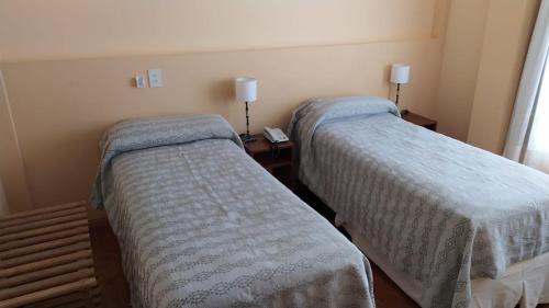 玛德琳港LOWCOST MADRYN的客房设有两张床和一张带台灯的桌子。