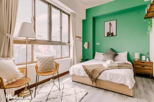台南海安艺术公寓民宿的绿色卧室配有床和椅子