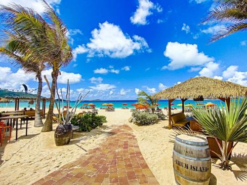 东方湾Maracuja 9, Orient Bay village, walkable beach at 100m的海滩上,有椅子和棕榈树,还有大海