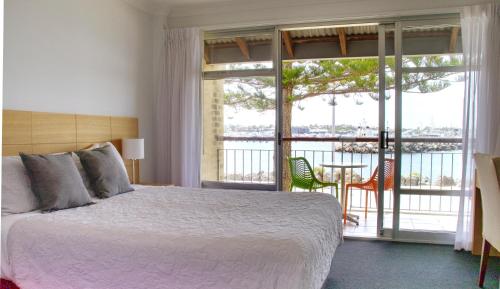 弗里曼特Harbourviewocean Views On Fishermans Wharf的一间带大床的卧室和一个阳台