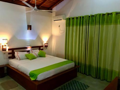 南塔拉拉Talalla Leisure的一间卧室配有一张带绿色窗帘的大床