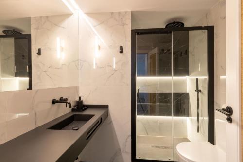 塞维利亚Salado Triana Suites by Valcambre的白色的浴室设有水槽和淋浴。